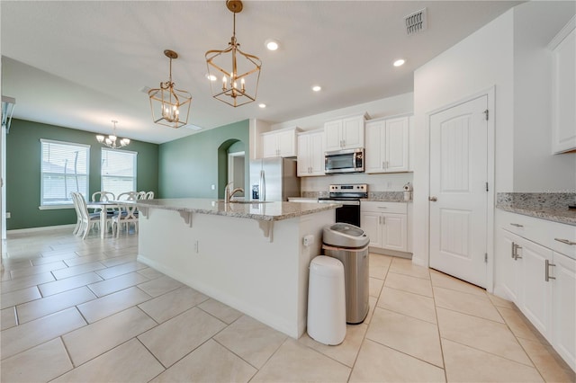 kitchen featuring a kitchen breakfast bar, a center island with sink, appliances with stainless steel finishes, and pendant lighting