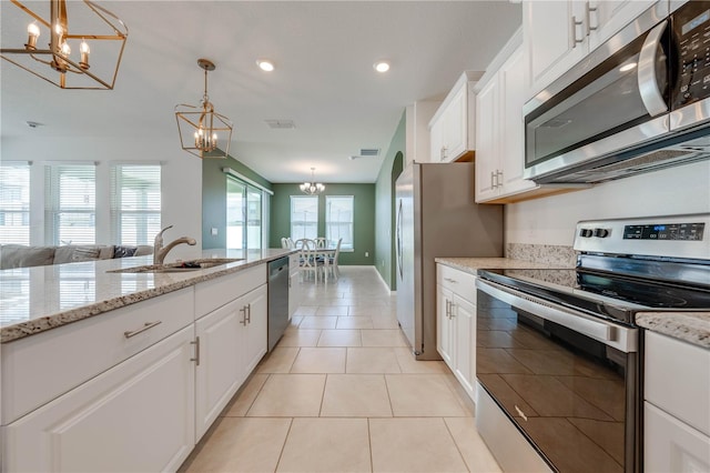 kitchen featuring pendant lighting, white cabinetry, appliances with stainless steel finishes, light tile patterned floors, and light stone countertops