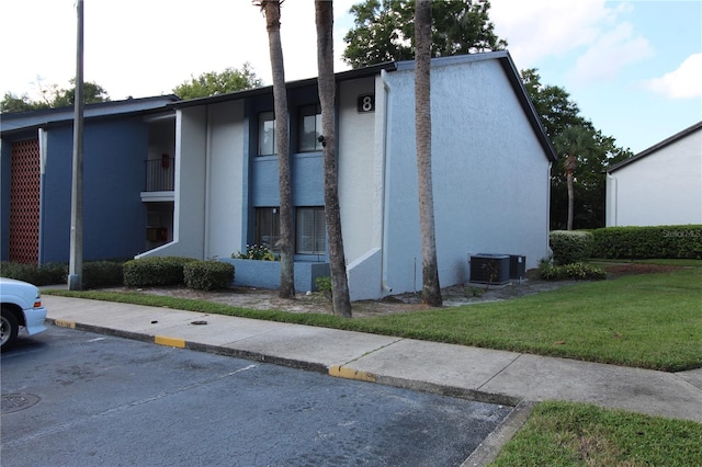 exterior space featuring a lawn, central AC, and a balcony