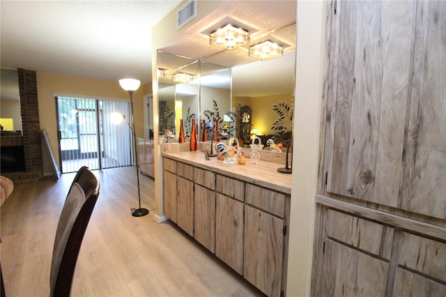 bathroom featuring a brick fireplace, vanity, and hardwood / wood-style floors