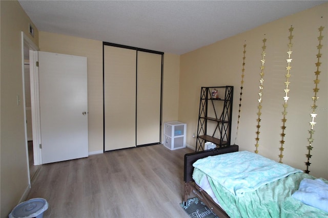 bedroom with light wood-type flooring, a closet, and a textured ceiling