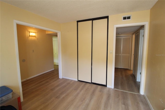 unfurnished bedroom with light hardwood / wood-style floors and a textured ceiling