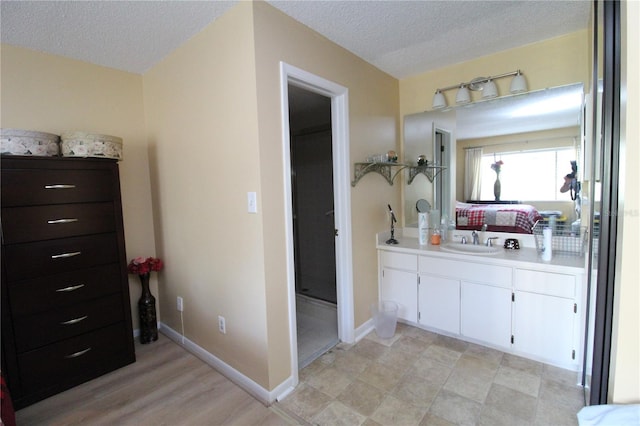 bathroom with a textured ceiling, wood-type flooring, and vanity