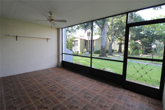 unfurnished sunroom with ceiling fan