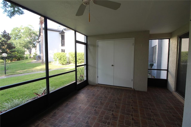 unfurnished sunroom with ceiling fan