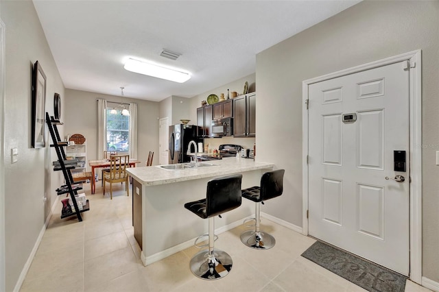 kitchen with appliances with stainless steel finishes, a breakfast bar, kitchen peninsula, pendant lighting, and sink