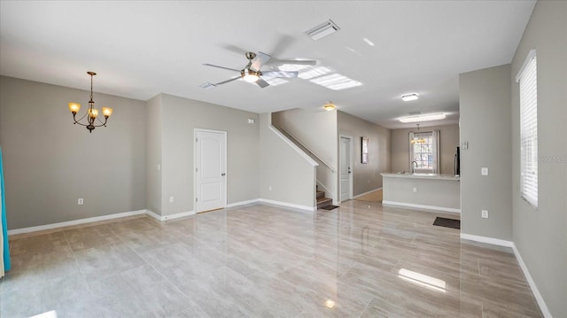 unfurnished living room with ceiling fan with notable chandelier