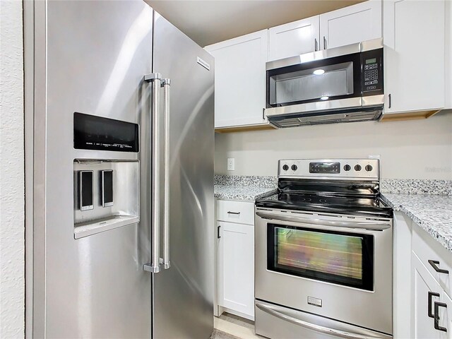 kitchen with light stone counters, appliances with stainless steel finishes, and white cabinetry