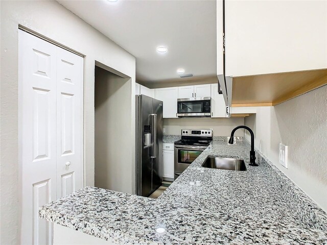 kitchen featuring appliances with stainless steel finishes, white cabinetry, sink, and light stone counters