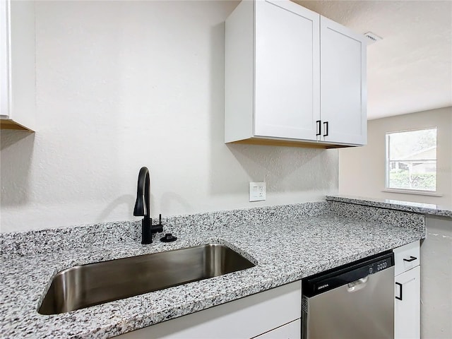 kitchen featuring light stone countertops, white cabinetry, dishwasher, and sink