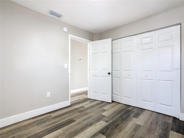 unfurnished bedroom with dark hardwood / wood-style floors and a closet