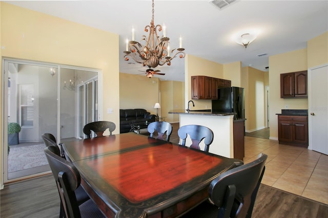 dining area with sink, light hardwood / wood-style floors, and ceiling fan with notable chandelier