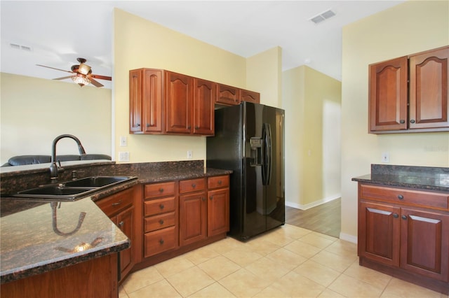 kitchen featuring ceiling fan, dark stone countertops, black fridge with ice dispenser, and sink