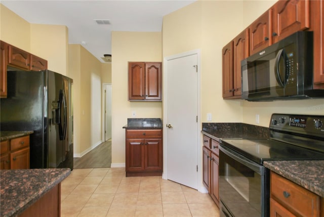 kitchen with black appliances, dark stone countertops, and light tile patterned floors