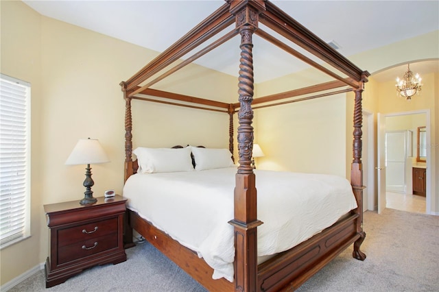 bedroom with connected bathroom, light colored carpet, an inviting chandelier, and multiple windows