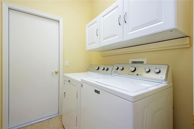 washroom with washer and clothes dryer, cabinets, and light tile patterned floors