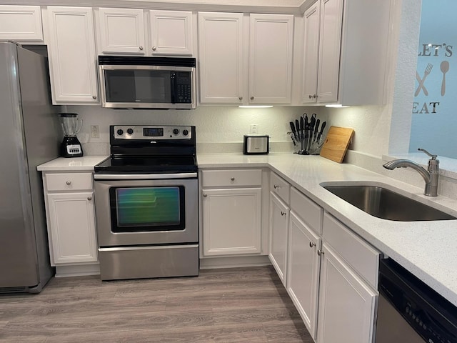 kitchen featuring white cabinetry, sink, light hardwood / wood-style flooring, and stainless steel appliances