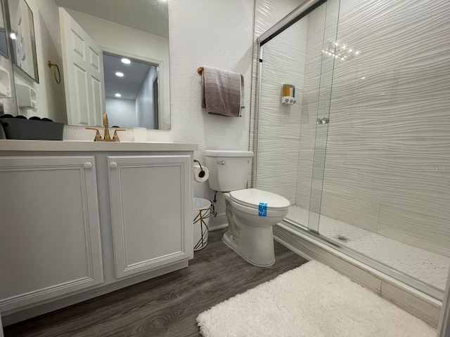 bathroom with a notable chandelier, walk in shower, hardwood / wood-style floors, vanity, and toilet