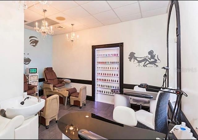 tiled office space with a notable chandelier and a paneled ceiling