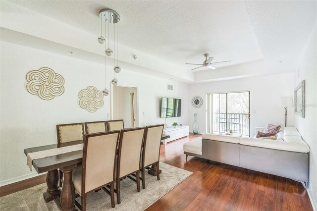 dining space featuring a textured ceiling, ceiling fan, and dark wood-type flooring