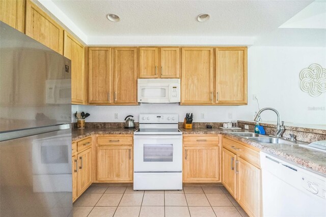 kitchen featuring a textured ceiling, white appliances, sink, and light tile patterned floors