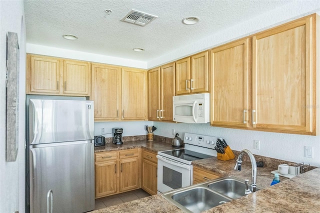 kitchen featuring white appliances, a textured ceiling, light tile patterned floors, and sink