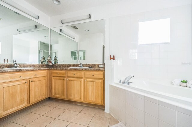 bathroom with tile patterned floors, tiled tub, and vanity