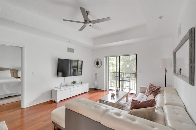 living room featuring a tray ceiling, hardwood / wood-style floors, and ceiling fan