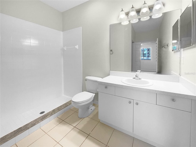 bathroom featuring a tile shower, vanity, tile patterned flooring, and toilet