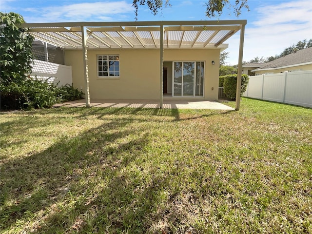 rear view of property featuring a pergola, a lawn, and a patio