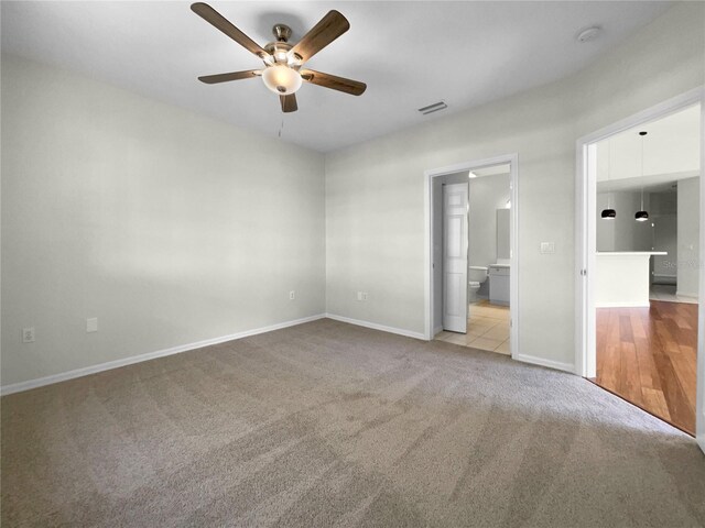 unfurnished bedroom with a walk in closet, ceiling fan, and light colored carpet