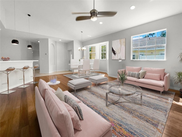 living room with ceiling fan with notable chandelier and hardwood / wood-style floors