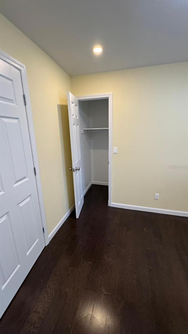 unfurnished bedroom featuring a closet and dark wood-type flooring