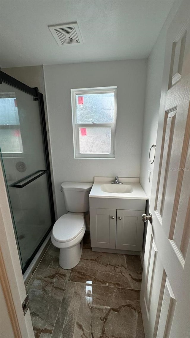 bathroom with vanity, a shower with shower door, and toilet