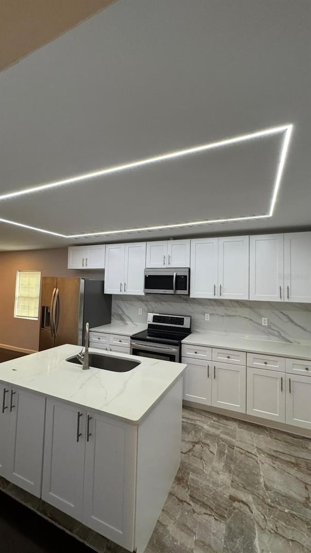 kitchen featuring sink, backsplash, white cabinetry, stainless steel appliances, and light stone counters