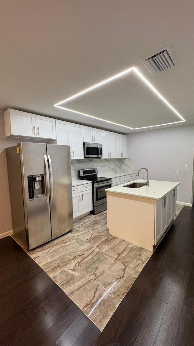 kitchen featuring light hardwood / wood-style flooring, stainless steel appliances, sink, white cabinets, and tasteful backsplash