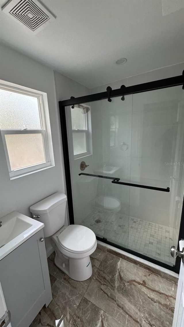 bathroom with vanity, a shower with shower door, and toilet