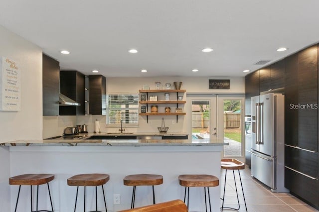 kitchen with a breakfast bar, sink, kitchen peninsula, light tile patterned floors, and high end fridge