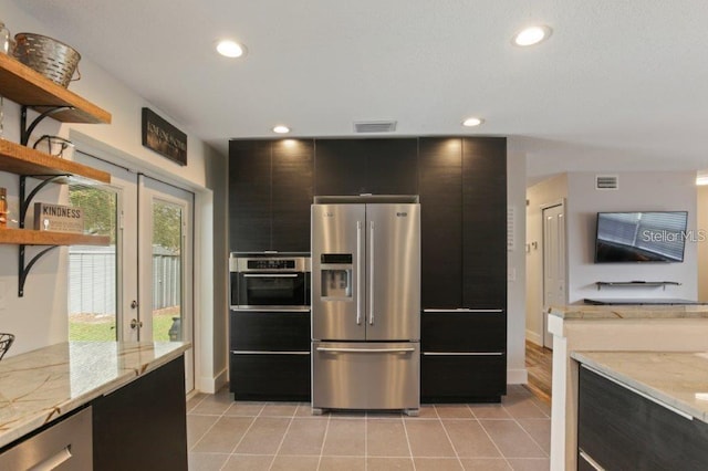 kitchen with light stone countertops, light tile patterned flooring, and appliances with stainless steel finishes