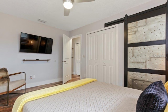 bedroom featuring ceiling fan, a barn door, and wood-type flooring