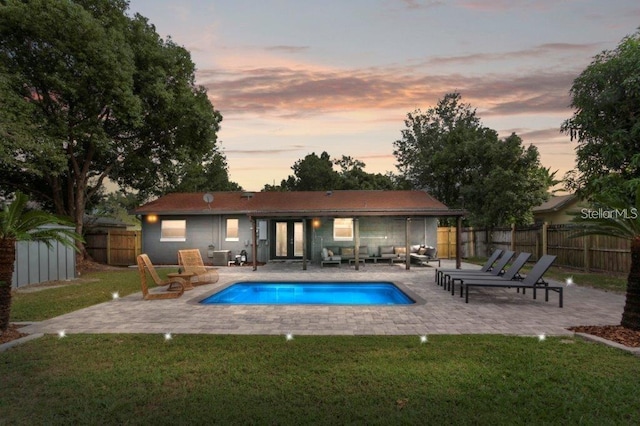 pool at dusk with a patio and a yard