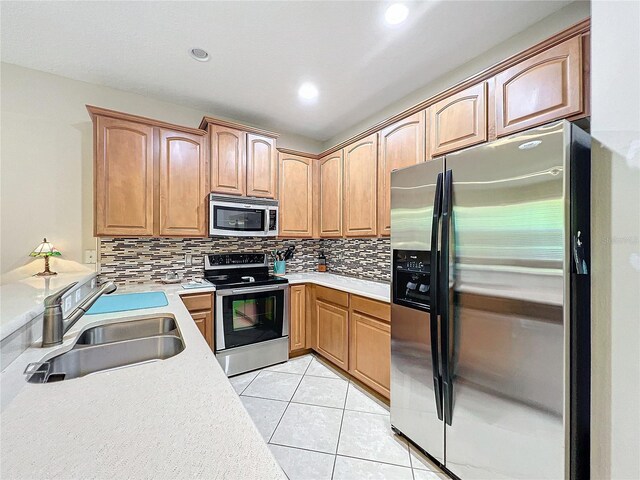 kitchen with appliances with stainless steel finishes, decorative backsplash, sink, and light tile patterned floors