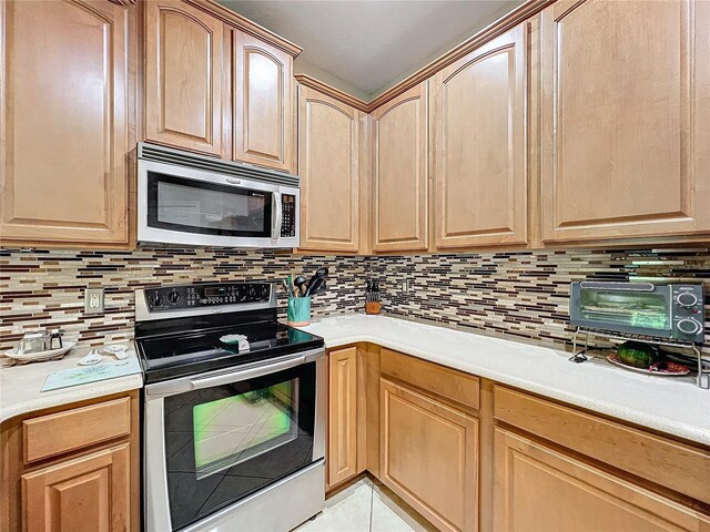 kitchen with decorative backsplash, appliances with stainless steel finishes, and light tile patterned flooring