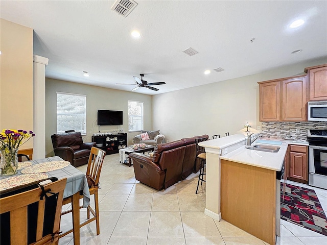 kitchen with sink, kitchen peninsula, appliances with stainless steel finishes, light tile patterned floors, and ceiling fan