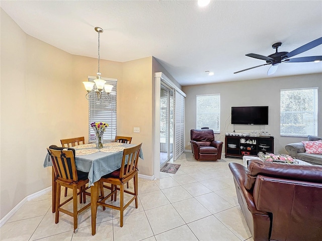 dining space with ceiling fan with notable chandelier, light tile patterned flooring, and a wealth of natural light