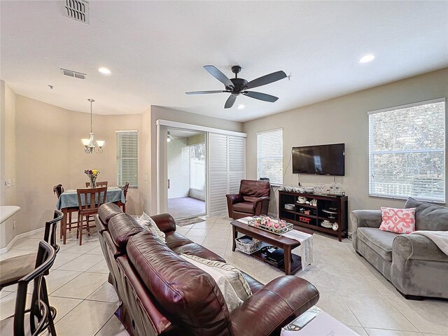 living room with ceiling fan with notable chandelier and light tile patterned floors