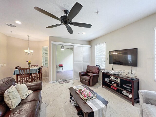 tiled living room featuring ceiling fan with notable chandelier