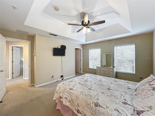 carpeted bedroom with a tray ceiling and ceiling fan