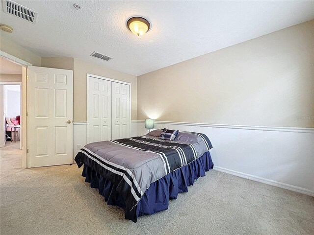 bedroom featuring carpet floors, a textured ceiling, and a closet