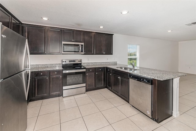 kitchen with dark brown cabinets, stainless steel appliances, kitchen peninsula, and sink